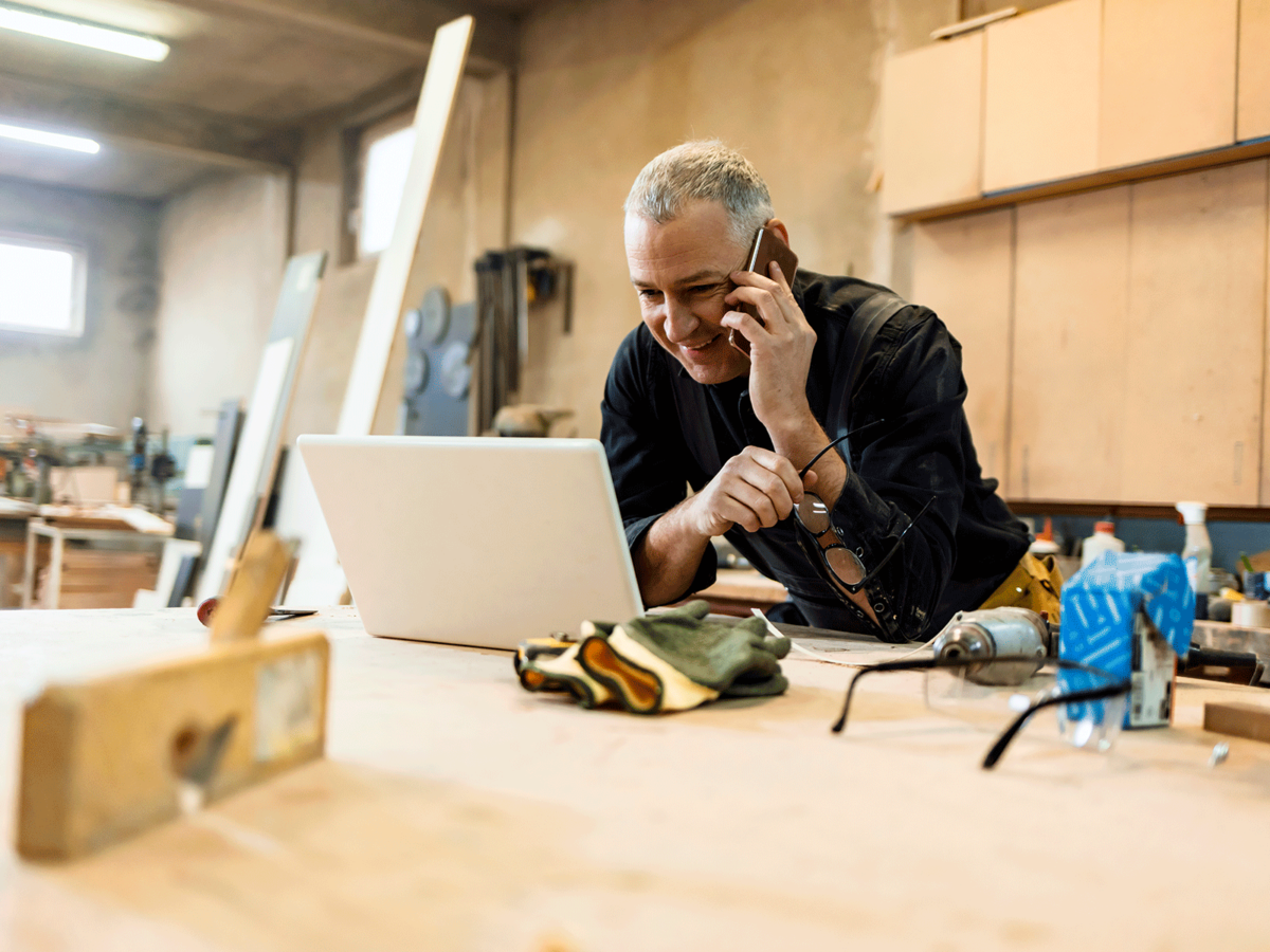 Aannemer kijkt tevreden naar facturen op laptop in DEDDO software gekoppelt aan boekhoudprogramma e-Boekhouden.nl