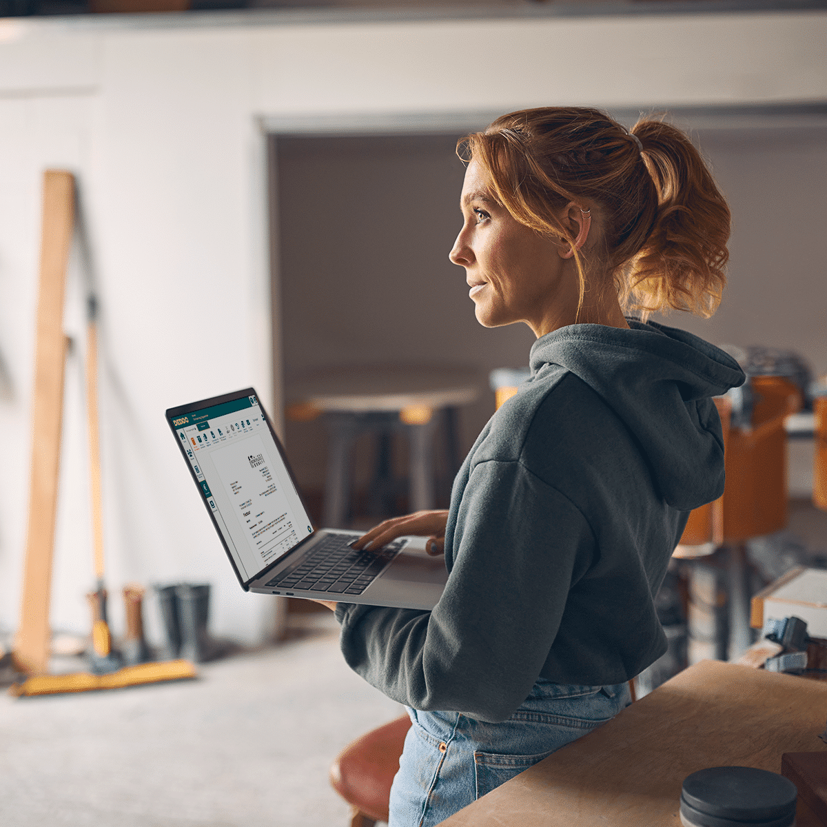 Vakvrouw op werkplaats maakt factuur in DEDDO op laptop