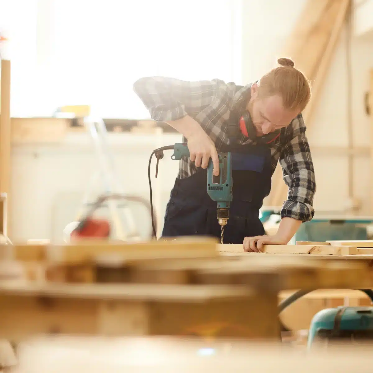 Meubelmaker boort in hout in de werkplaats