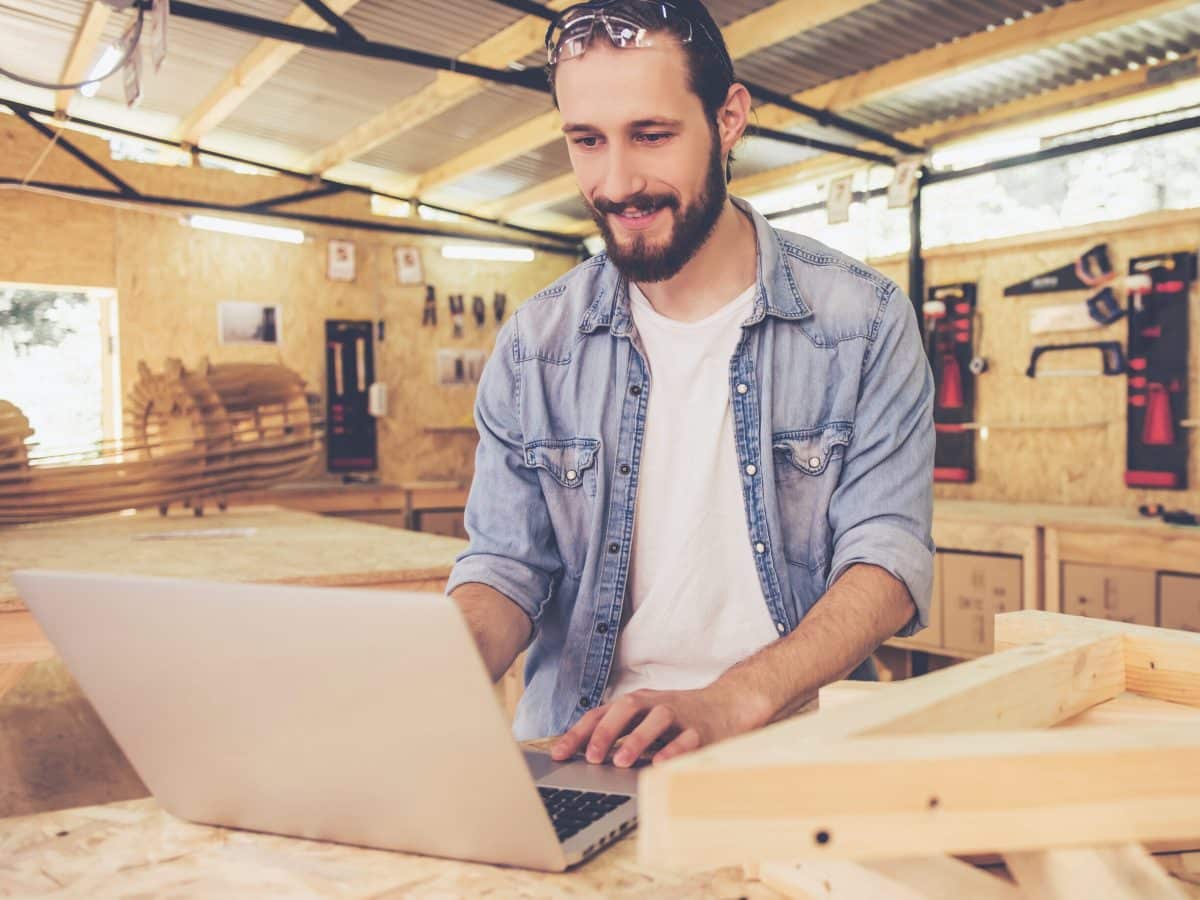 Timmerman is blij met calculatie op laptop scherm in werkplaats