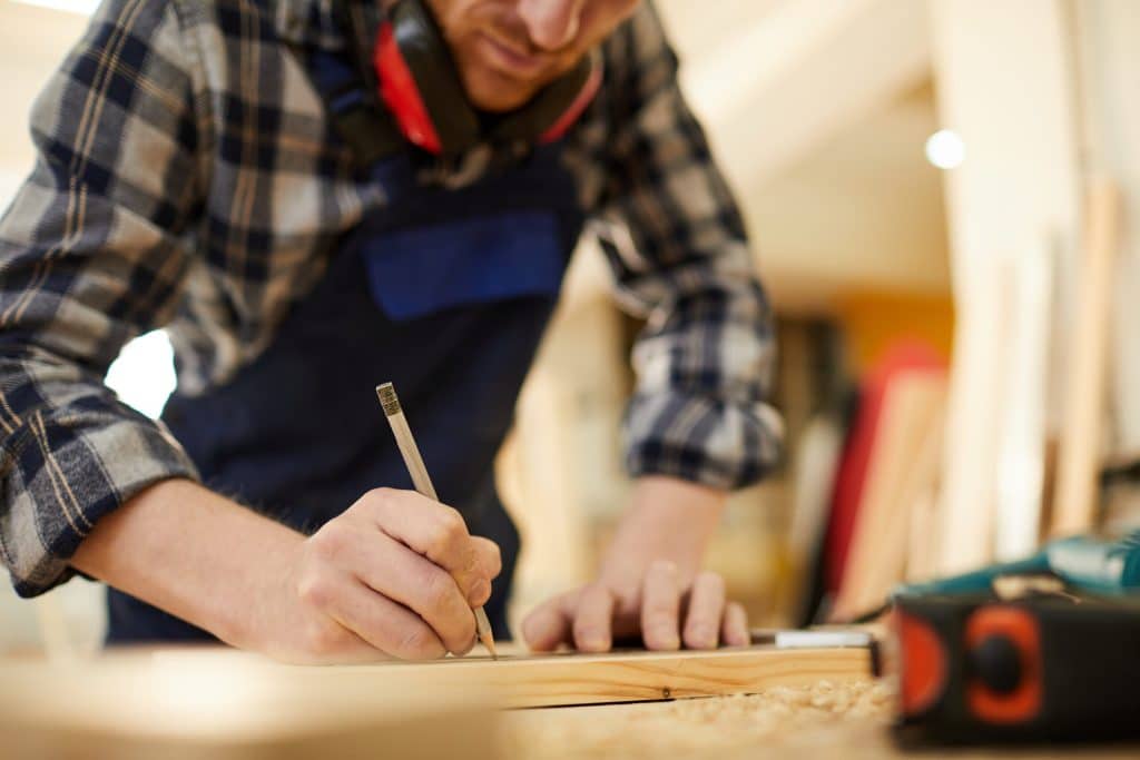 Aannemer meet het hout in de werkplaats op basis van de calculatie van de klus