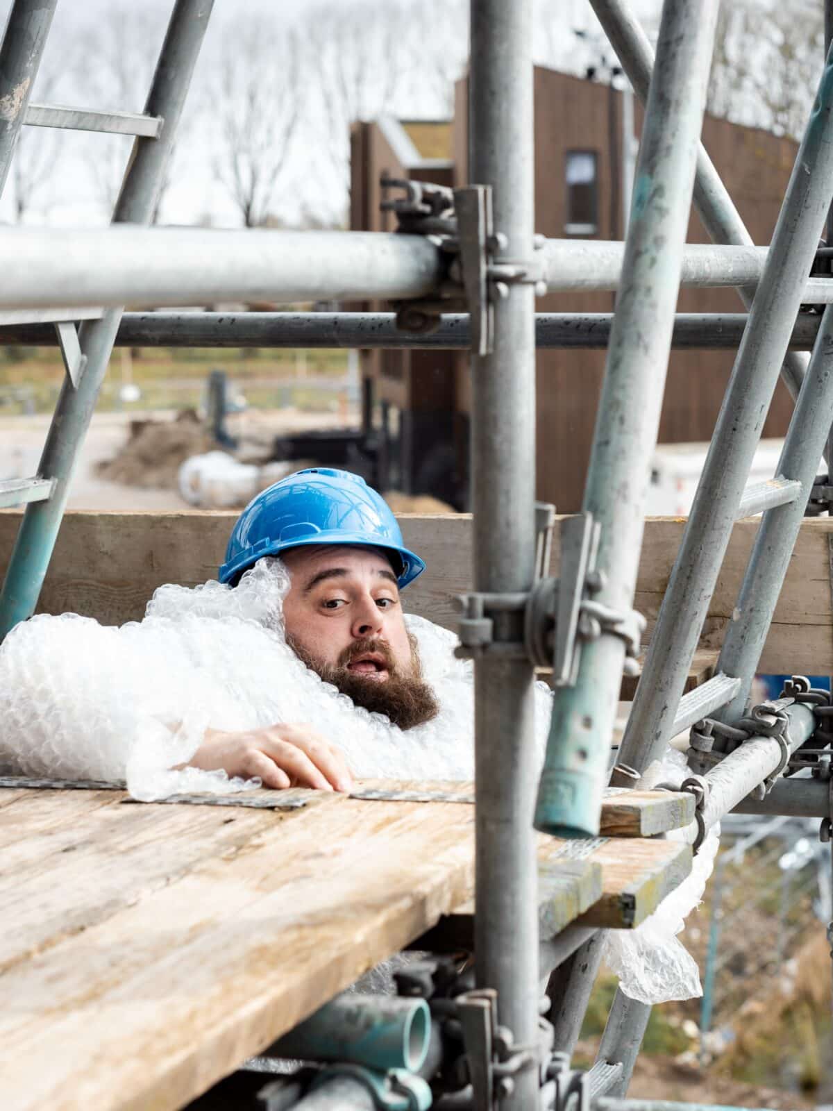 Man zakkend door steiger op de bouwplaats
