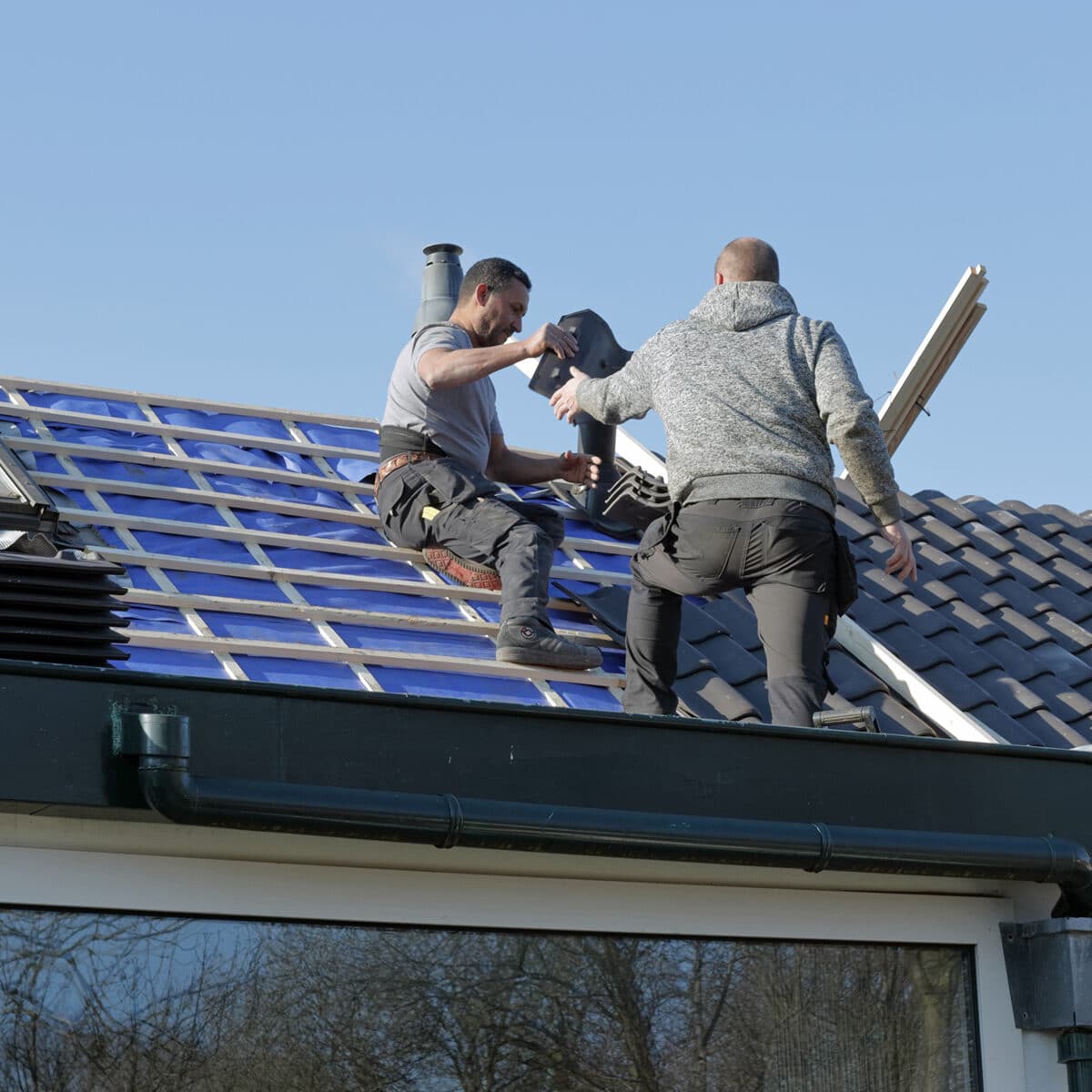 Dakdekkers helpen elkaar op het dak
